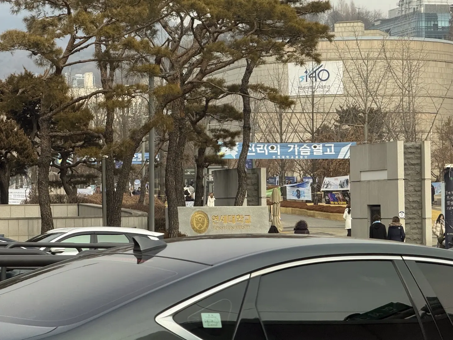 전시 안내가 걸린 건물 입구와 도로 위의 자동차
