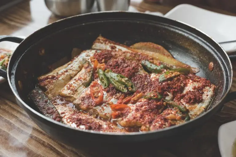 붉은 양념과 파, 생선이 담긴 검은 냄비의 갈치조림