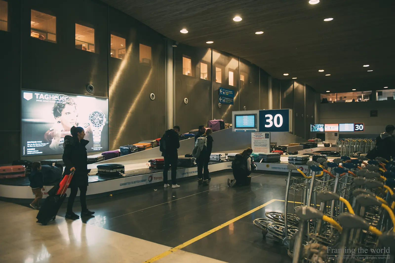 전광판에 30번이 표시된 공항 수하물 수취대와 여행객들