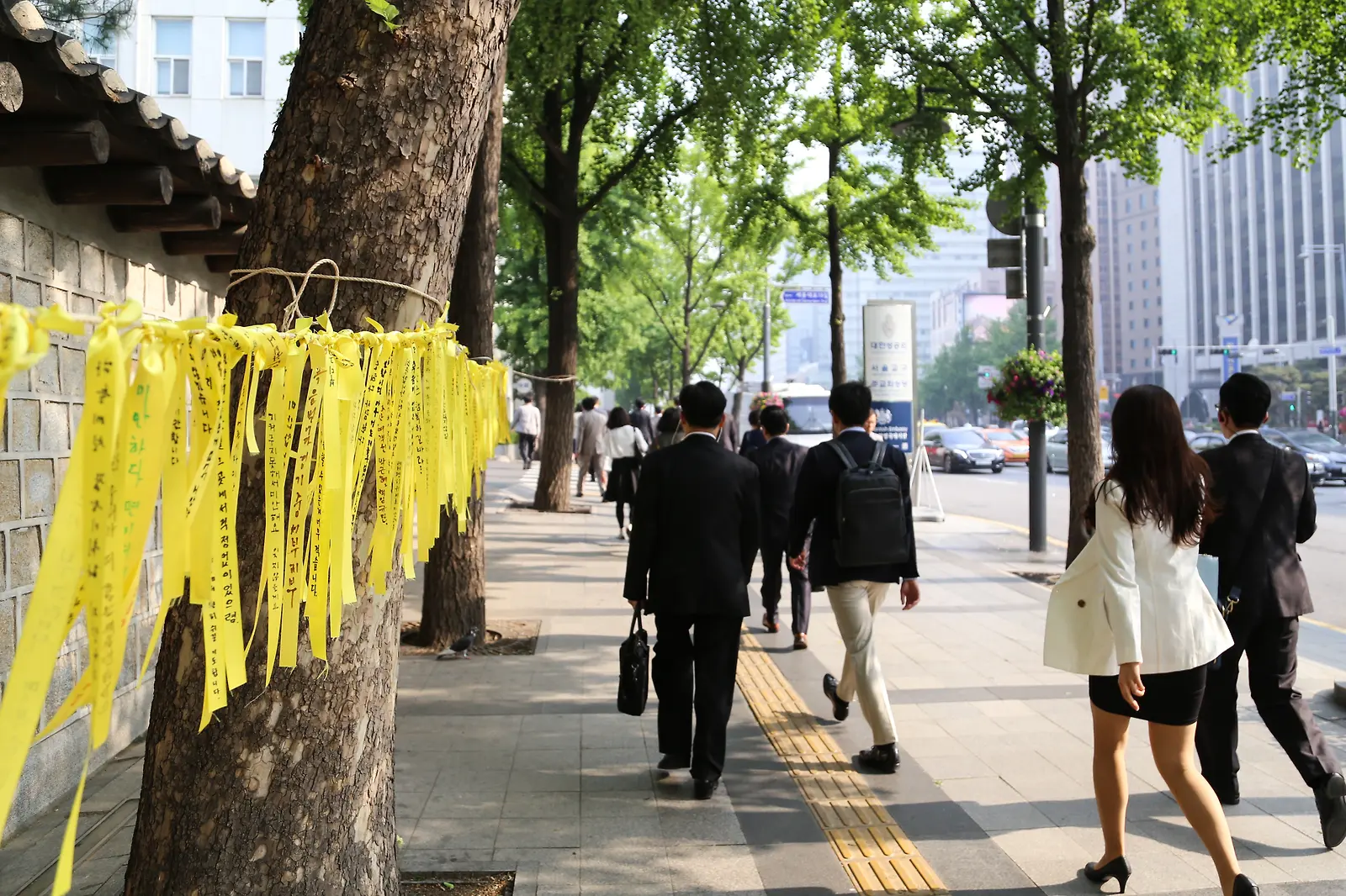 노란 추모 리본이 걸린 길을 걸어가는 사람들