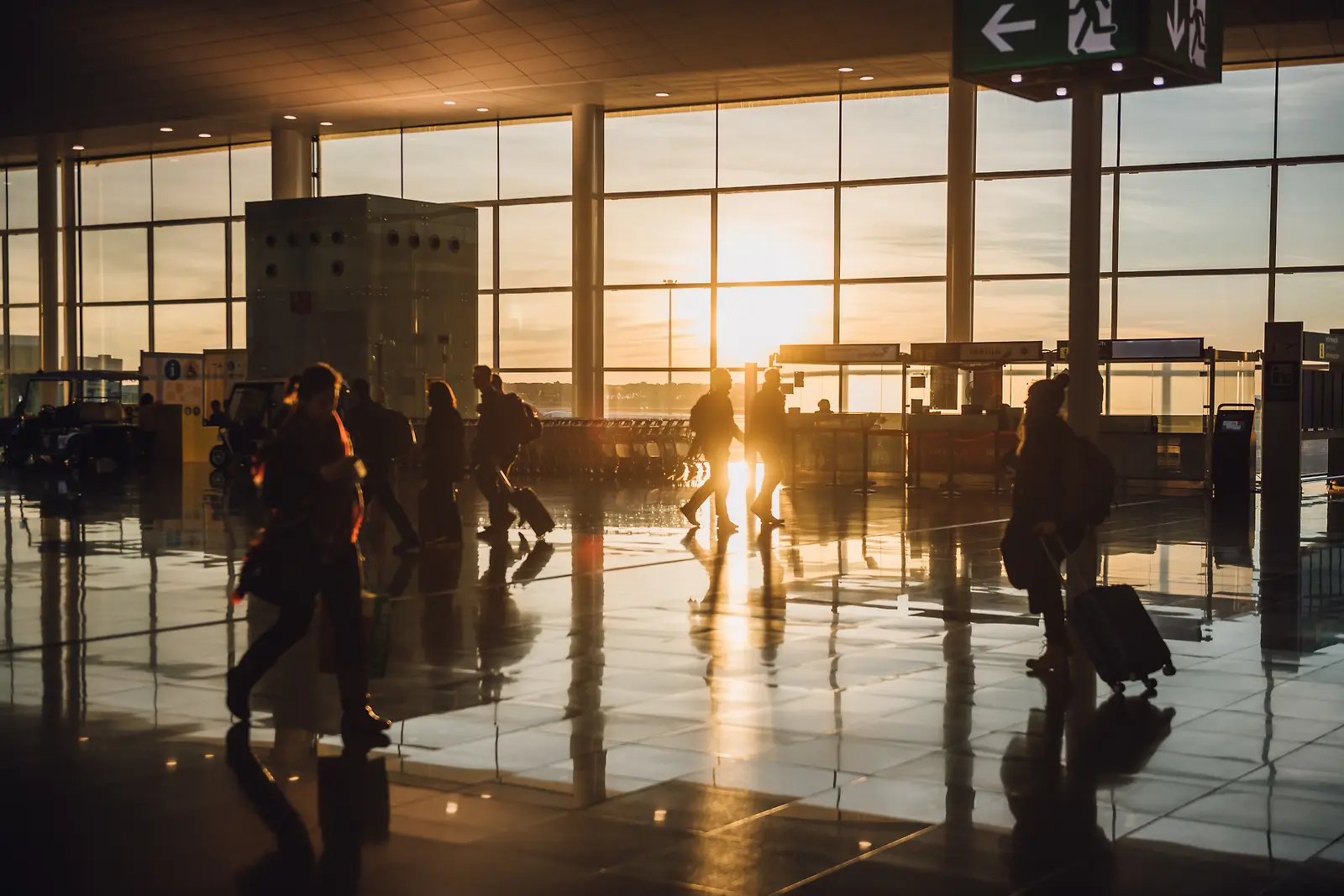 해질녘 유리창으로 빛이 들어오는 공항 안의 여행객들
